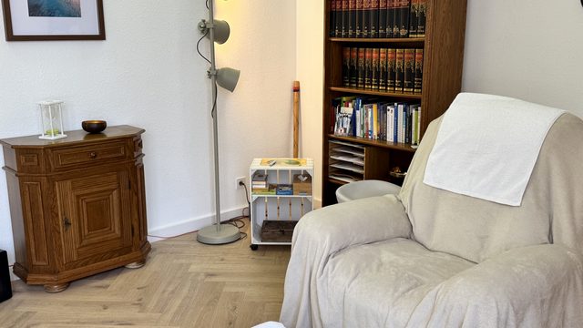 Hypnoseecke mit Sessel, Bücherregal und warmem Licht in der DHI Hypnosepraxis Aschaffenburg